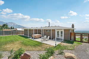 Rear view of house featuring french doors, a fenced backyard, a hot tub, brick siding, and a patio