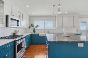 Kitchen with blue cabinetry, stainless steel appliances, plenty of natural light, wood finished floors, and recessed lighting
