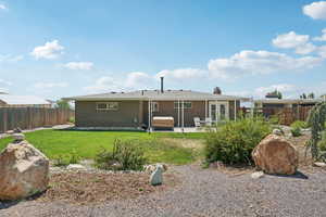 Rear view of house featuring a fenced backyard, a patio, a chimney, and a hot tub