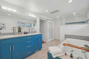 Full bathroom with double vanity, a walk in shower, recessed lighting, and a bath