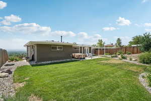 Rear view of house with a fenced backyard, brick siding, and a patio