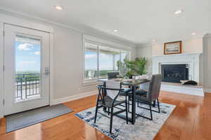 Dining space featuring crown molding, light wood-style floors, a glass covered fireplace, and recessed lighting