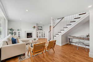 Living room featuring recessed lighting, light wood-style floors, stairs, and a fireplace with raised hearth
