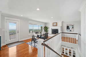 Living room featuring a glass covered fireplace, ornamental molding, light wood finished floors, and recessed lighting