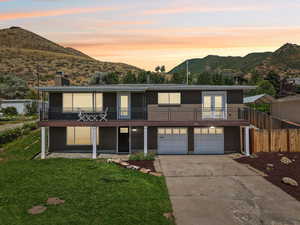 View of front facade featuring a mountain view, a garage, concrete driveway, and a chimney