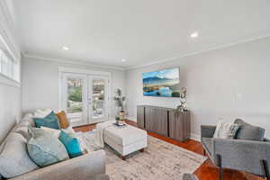 Living room with crown molding, wood finished floors, recessed lighting, and french doors