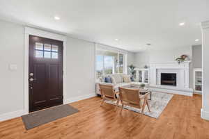 Foyer entrance with light wood-style floors, recessed lighting, and a fireplace with raised hearth