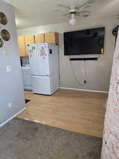 Kitchen featuring white appliances, a ceiling fan, light wood finished floors, and light colored carpet