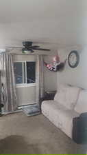 Carpeted living room with ceiling fan and baseboard heating