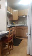 Kitchen with light wood-style floors, freestanding refrigerator, light countertops, and stove