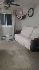 Carpeted living room with a ceiling fan and a baseboard heating unit