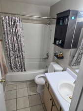 Bathroom featuring tile patterned flooring, shower / bath combo with shower curtain, and vanity