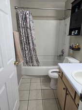 Bathroom featuring shower / bathtub combination with curtain, vanity, and tile patterned flooring
