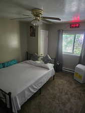 Bedroom featuring carpet floors, a baseboard heating unit, and a ceiling fan
