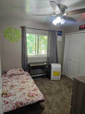 Bedroom with carpet flooring, a ceiling fan, baseboard heating, and a closet