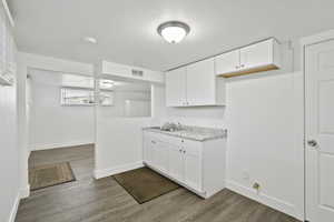 Kitchen featuring dark wood-style flooring, white cabinets, and light stone countertops