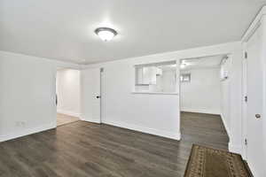 Empty room featuring baseboards and dark wood-style flooring