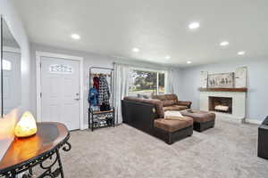 Living area featuring carpet floors, recessed lighting, and a fireplace