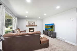 Carpeted living area with recessed lighting and a fireplace