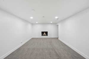 Unfurnished living room featuring a fireplace, recessed lighting, and carpet flooring