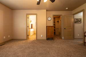 Primary bedroom with a walk-in closet, carpet flooring, private bath