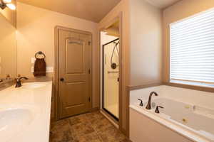 Full primary bath featuring a tub with jets, a shower stall, and double vanity