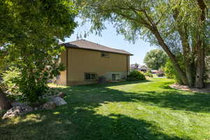 View of the property side yard with a lawn and stucco siding