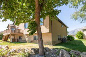 Back of property featuring a deck with mountain view, stairway, a yard, and stucco siding