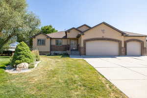 Ranch-style home featuring an attached garage, stucco siding, driveway, and a front lawn