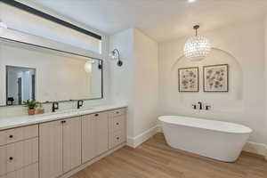 Full bathroom with vanity, a freestanding bath, and wood finished floors