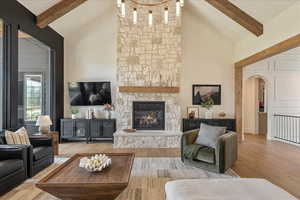 Living room featuring arched walkways, high vaulted ceiling, beam ceiling, wood finished floors, and a fireplace