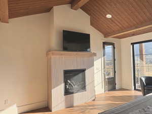 Living room with wood ceiling, wood finished floors, a glass covered fireplace, and recessed lighting