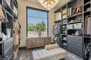 Walk in closet with a chandelier and wood finished floors