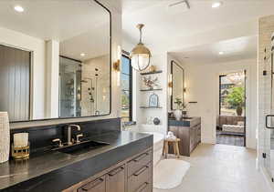 Bathroom with a stall shower, two vanities, ensuite bathroom, and recessed lighting