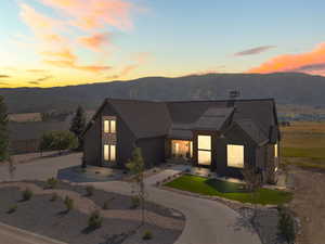 View of front of house featuring a mountain view, stone siding, a standing seam roof, a metal roof, and curved driveway