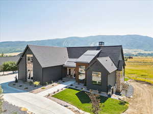 View of front of house featuring stone siding, roof with shingles, a standing seam roof, and a mountain view
