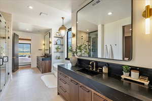 Ensuite bathroom with a shower stall, two vanities, and recessed lighting