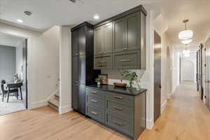 Hallway with light wood finished floors, stairway, and recessed lighting