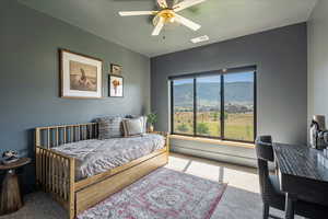 Bedroom with carpet flooring, a desk, a ceiling fan, and a mountain view