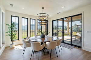 Dining room featuring a chandelier, light wood-style flooring, recessed lighting, and french doors