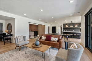 Living room with a barn door, light wood-style floors, and recessed lighting