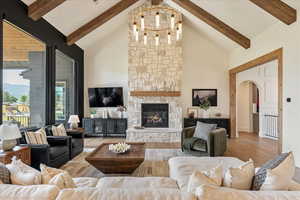Living area with arched walkways, high vaulted ceiling, beamed ceiling, wood finished floors, and a stone fireplace