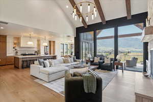 Living area featuring light wood-style floors, a mountain view, beamed ceiling, high vaulted ceiling, and recessed lighting