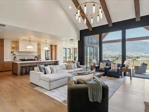 Living area featuring light wood-style floors, a mountain view, beamed ceiling, high vaulted ceiling, and recessed lighting