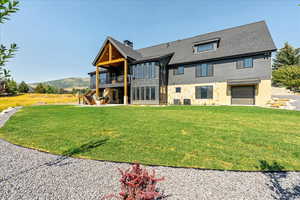 Back of property featuring stone siding, stairway, a yard, a sunroom, and a chimney
