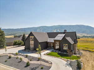 View of front of house with stone siding, a mountain view, and a chimney