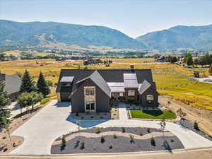 View of front of home with concrete driveway, stone siding, a mountain view, a chimney, and a garage