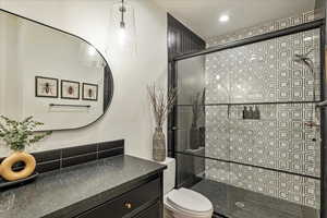 Full bath with tiled shower, vanity, and recessed lighting