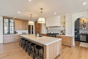 Kitchen with decorative backsplash, a large island, wine cooler, a breakfast bar, and high end stainless steel range