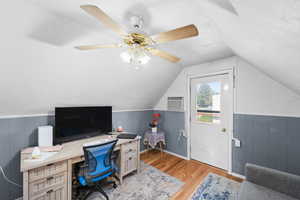 Office area featuring light wood-type flooring, lofted ceiling, wainscoting, and a ceiling fan